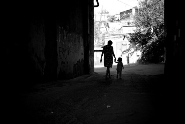 Una niña de la mano de una mujer, mientras caminan por la calle.