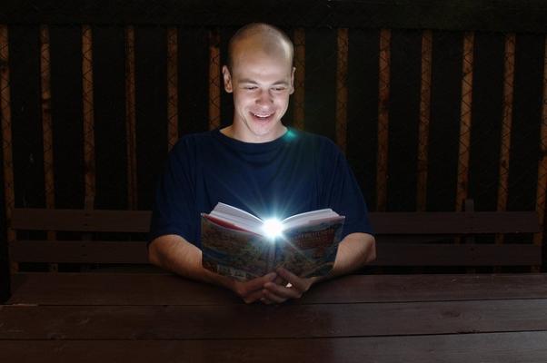 Una persona leyendo un libro del que parece proyectarse una luz, como ejemplo de que leer puede ayudarte a potenciar tu liderazgo.