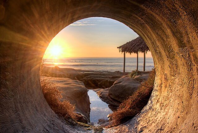Una fotografía donde se puede ver una playa paradisiaca al otro lado de un tunel, como forma de representar el liderazgo visionario.