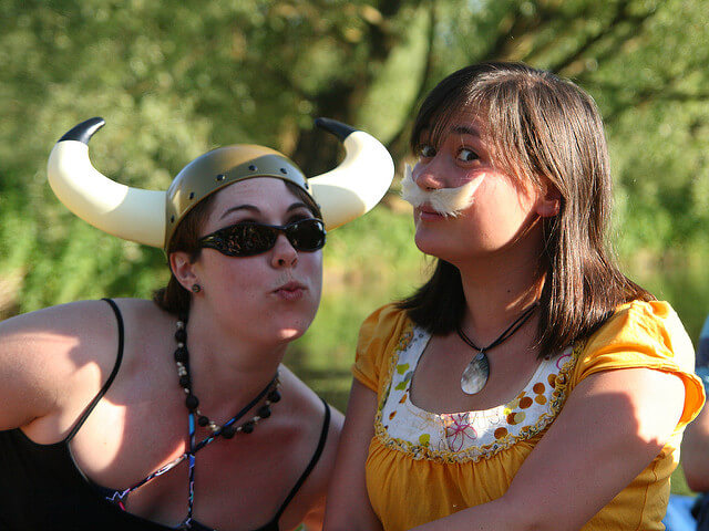 Dos chicas jóvenes disfrazadas de vikingos, o bien Asterix y Obelix. Una de ellas lleva un casco con cuernos y otra un gran bigote rubio.