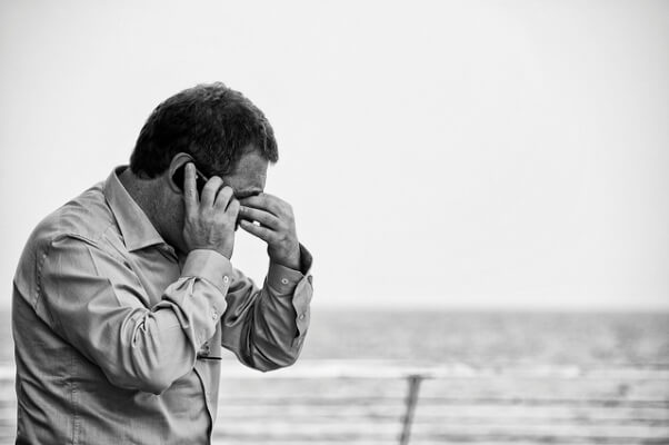 Una fotografía de un hombre que parece preocupado y atravesando momentos difíciles, hablando por teléfono móvil.